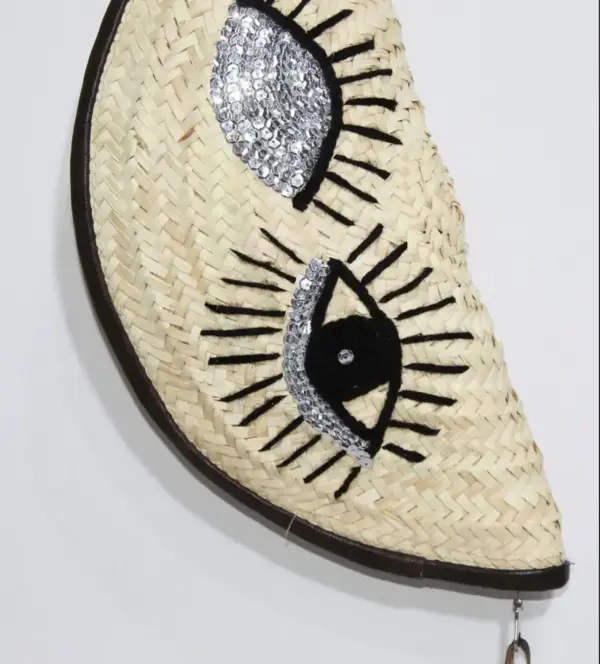 acb8d246256e5a3e91d76148856eb5c546e3b6ac89ea4adaf167d46b44eb6844-1.webp Eyes Clutch – Handwoven Palm Leaf Bag with Embroidered Eyes Design